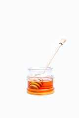 jar of bee honey with a spoon for honey on a white background