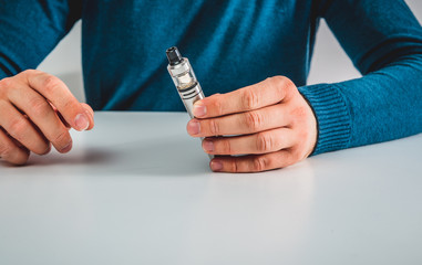 The man is holding an e-cigarette for vaping. The concept of quitting analog cigarettes, nicotine...