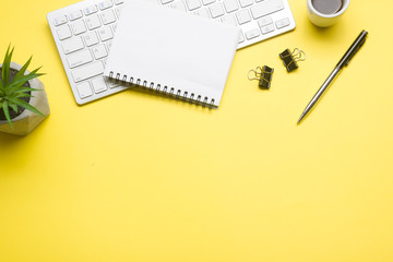 Yellow desk office with laptop, smartphone and other work supplies with cup of coffee. Top view...