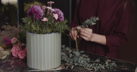 Woman florist prepares a bouquet, chooses flowers. Female hands close-up
