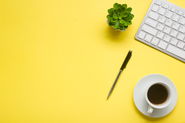 Yellow desk office with laptop, smartphone and other work supplies with cup of coffee. Top view...