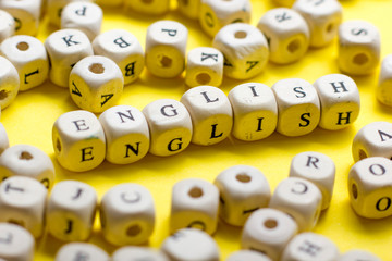 Word english made with block wood letters next to a pile of other letter over wooden table