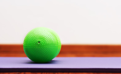 Small Peanut Shaped Exercise Ball on violet yoga mat. Copy space