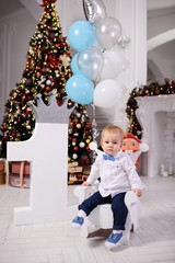 Fototapeta na wymiar baby-little boy celebrates birthday and new year on the background of a huge unit and Christmas tree.