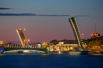 Fototapeta na wymiar Single-leaf bascule bridges at sunrise (Saint Petersburg, Russia). Russian text (on flags) translation: Welcome