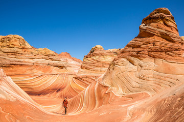 Young man hiking through Coyote Buttes and the famous Wave feature of Arizona.