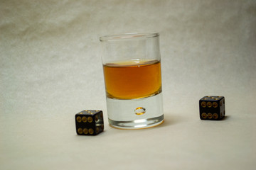 Glass with cognac on a light background with dices