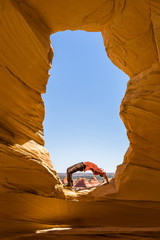 Yoga in the wilderness, back bend under arch inside a window overlooking the Arizona desert.