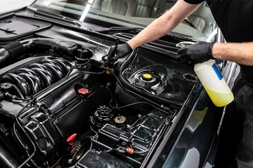 Car wash worker cleaning car engine