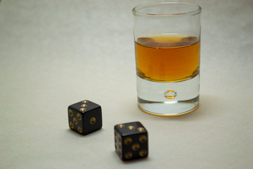 Glass with cognac on a light background with dices