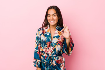 Young indian woman wearing a kimono pajama cheerful and confident showing ok gesture.