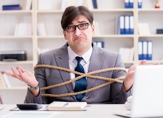 Businessman tied up with rope in office