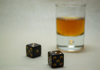 Glass with cognac on a light background with dices