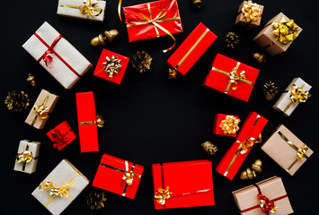 Christmas gifts boxes round frame, red and gold colors on black dark background - top view