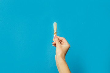 Female hand holds a stick of ice cream on a blue background. Hot summer concept, a pair of lovers, lovers. Flat lay, top view