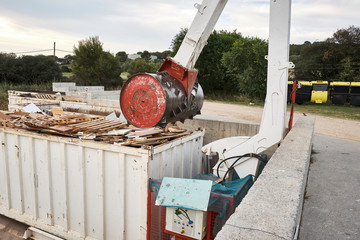Waste garbage compactor working on a dumpster bin in an outdoors municipal public dumb collector. Recycle machine. Environment pollution awareness.