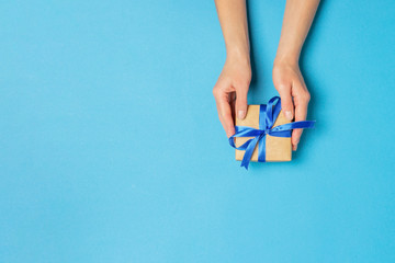 Female hand holds, takes, get a gift on a blue background. Concept gift, wedding, valnetina day....