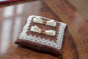brown pillow with wedding rings