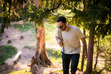 Happy bearded man traveler with backpack walking in forest. Tourism, travel, adventure, hike concept - smiling young man walking with backpack in woods. Concept of clean air and healthy lifestyle.