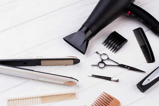 Hairdresser tools and accessories on wooden table. Hair straightener, combs, scissors and hair dryer. Working equipment of professional hairdreseser.