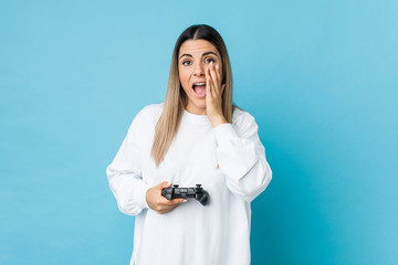 Young caucasian woman holding a game controller shouting excited to front.