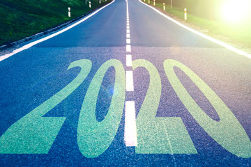 Concept of New Year 2020 Celebration. Word 2020 on highway road during golden sunset.