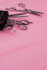 Hair cutting scissors for hairdresser in beauty salon. Professional hairdressing scissors on pink wooden background.