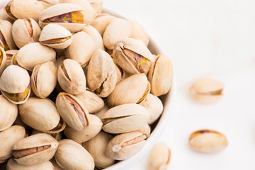 Bowl of roasted pistachios on a white background