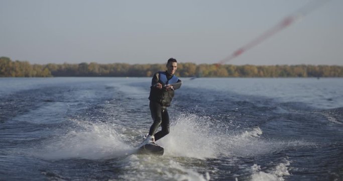 Young man wakeboarding on river
