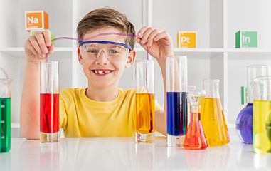 Cheerful boy doing chemistry experiment in lab