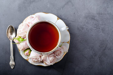 Tea time backdrop. Top-down still life with vintage white porcelain tea cup with gentle pink roses...