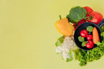 Variety of vegetables and frying pan on a blackboard, top view. Vegan and healthy concept.