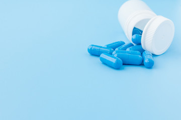 Blue capsules, pills on a blue background. Capsules in a white jar. Vitamins, nutritional...