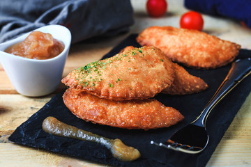 Four hand pie homemade with tomato and egg accompanied with applesauce and tomatoes cherry. Front view, no people