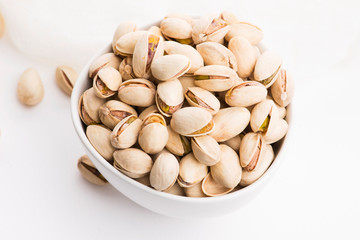 Bowl of roasted pistachios on a white background