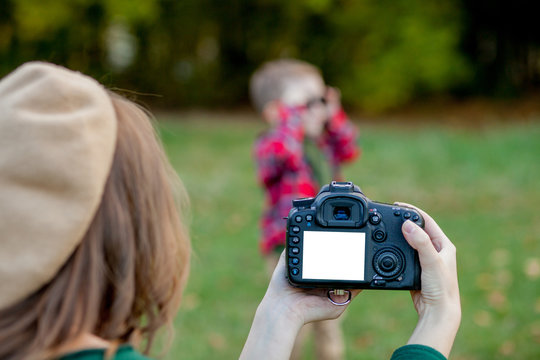 Woman photographer photographing the child to spend outside in the park