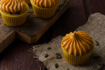 Pumpkin cupcakes with pumpkin-caramel cream wooden Background
