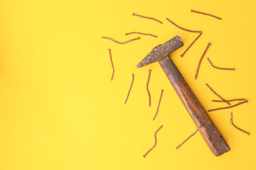 Old hammer and rusty nails. Yellow background. Copy space