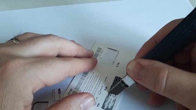 Turin, Piedmont, Italy. April 2019. The SIM card of the main Italian telephone company. A Caucasian man hand removes the film that hides the PIN and PUK codes. 30fps