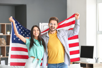 Happy young couple with national flag of USA at home