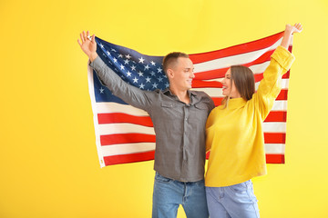 Happy young couple with national flag of USA on color background