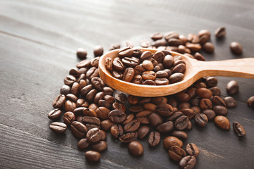 Spoon with roasted coffee beans on wooden background