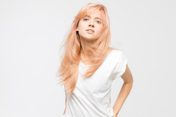 Fototapeta premium Close up studio portrait of young haughty blonde girl in white t-shirt. Woman looks arrogant at the camera. Disgruntled, angry and irritated female. Emotions concept. Copy space.