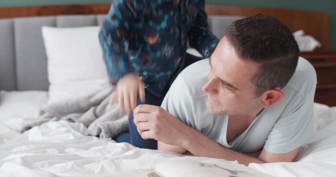 Blond boy playing with dad in bedroom, wrestling playful having fun close realtionship with father