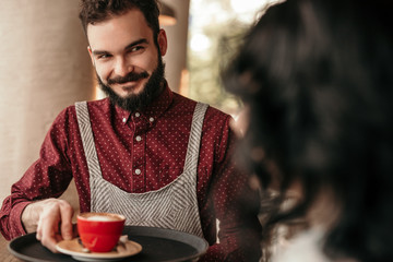 Smiling waiter giving coffee to customer