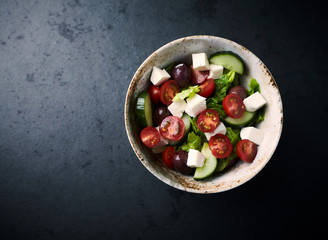 Salad with Kalamata Olives, Cucumber Cherry Tomatoes and Feta Cheese on black Stone Background. Healthy Snack Idea. Top view. Copy space. 