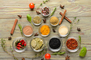 Bowls with different spices on wooden background