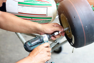 Worker hand tightening or loosening a nut of a bolt with a drill for wheel of small car. Automotives concept.