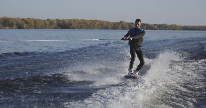 Young man wakeboarding on river