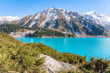 Naklejka na ściany i meble Lake with turquoise water surrounded by a mountain massif. Big Almaty lake in the mountains. Kazakhstan